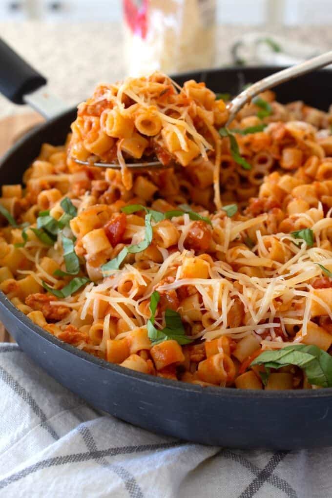 spoonful of ground chicken pasta in a black pan