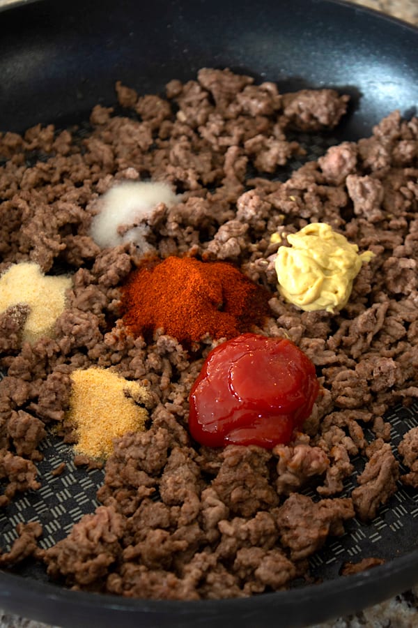 adding spices to hamburger helper meat