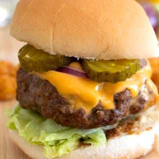 front view of a cheeseburger with condiments in the background