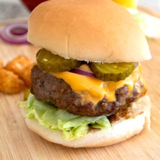 burger on cutting board with condiments in background