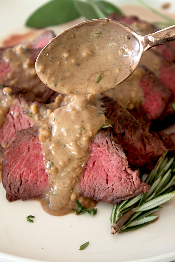 spooning pan sauce over medium rare steak