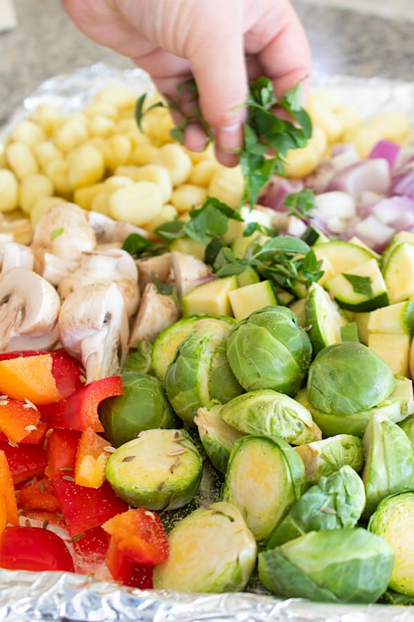 adding fresh herbs to sheet pan gnocchi