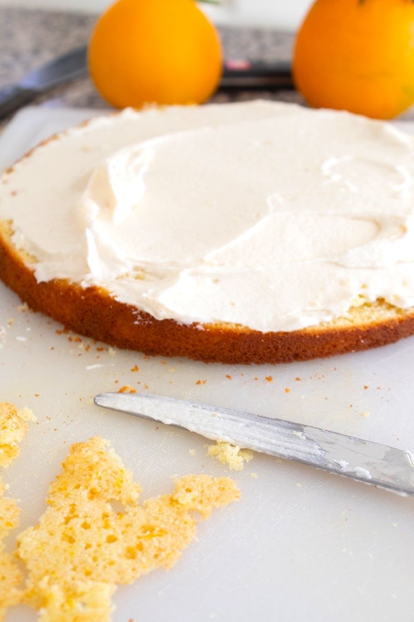 baked cake being topped with frosting