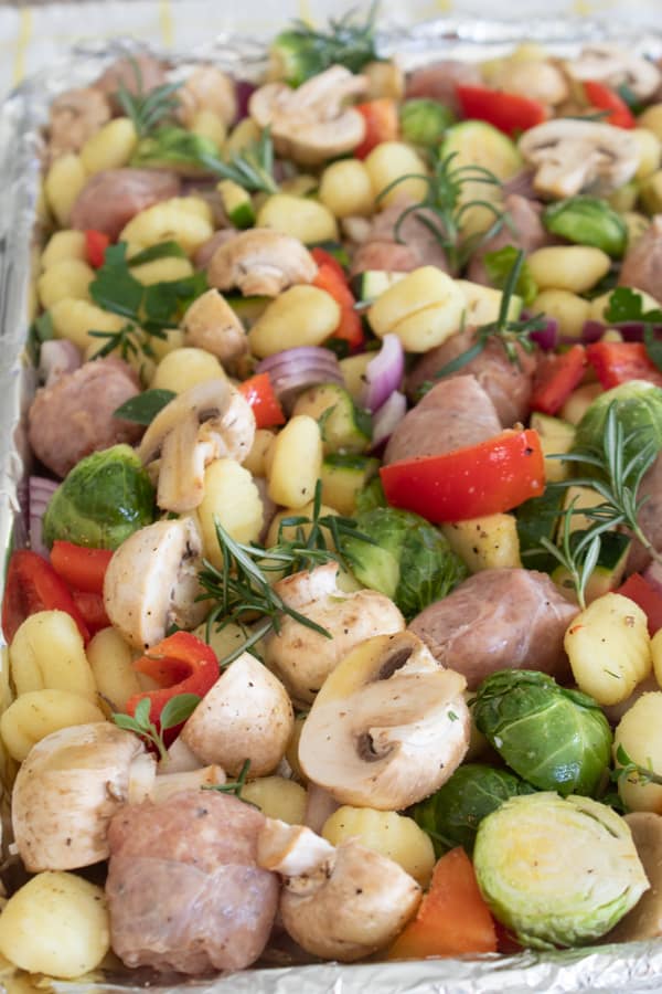 chopped vegetables gnocchi and sausage on a sheet pan