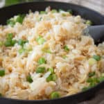 black pan full of cooked rice pilaf garnished with green onion