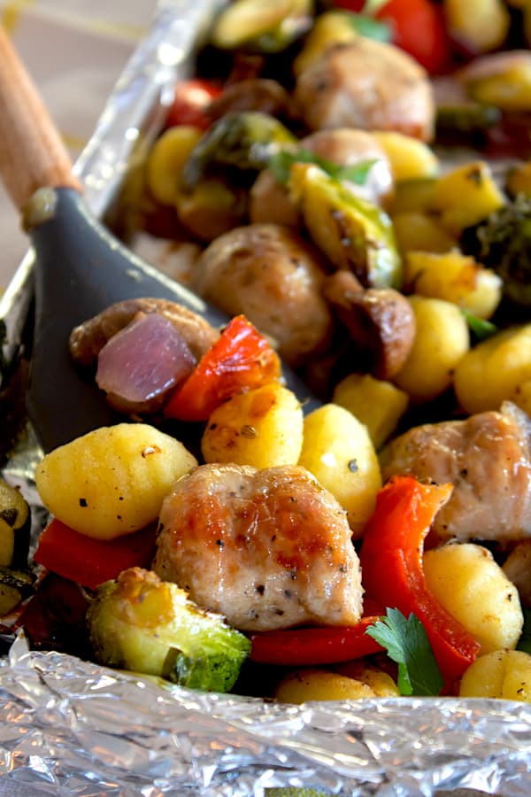 a spatula showing gnocchi and sausage cooked on a sheet pan