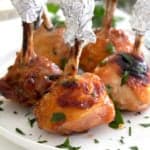 chicken lollipops garnished with parsley on a white plate