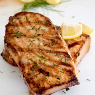 grilled swordfish with lemons in background