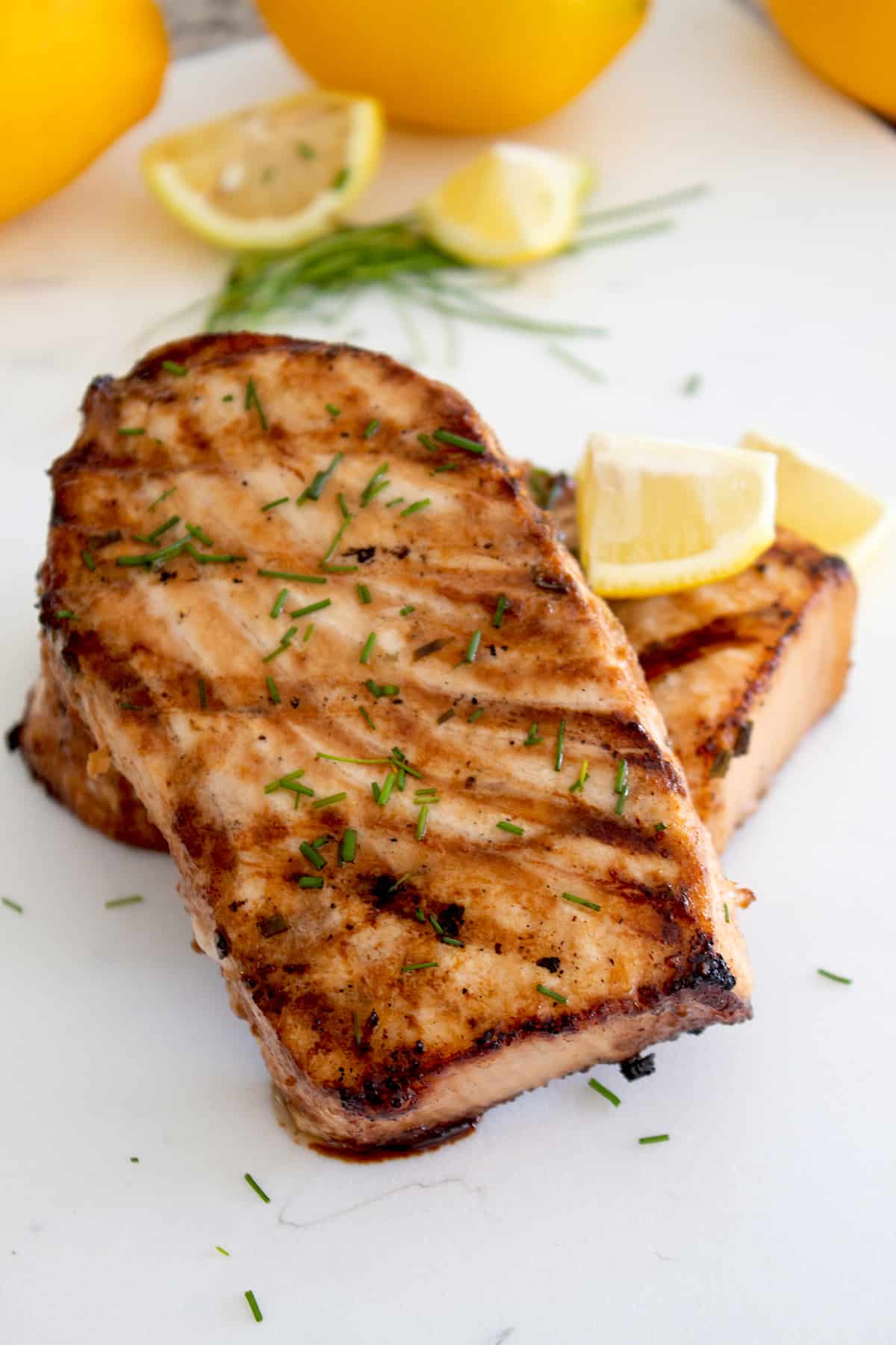 grilled swordfish with lemons in background