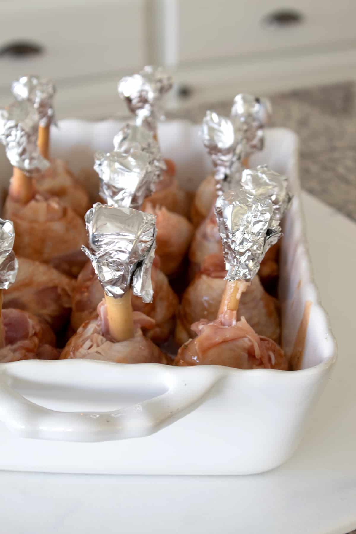 chicken lollipops marinating in a casserole dish