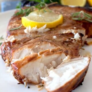 cut and sliced marinated swordfish with lemon and rosemary garnish