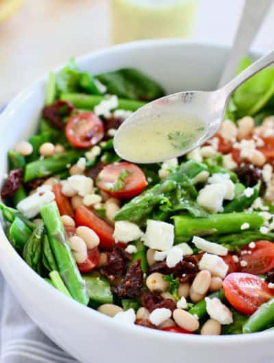 asparagus salad being tossed with lemon vinaigrette