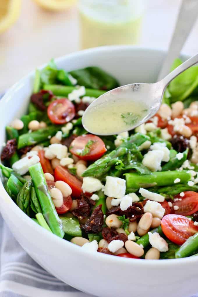 asparagus salad being tossed with lemon vinaigrette