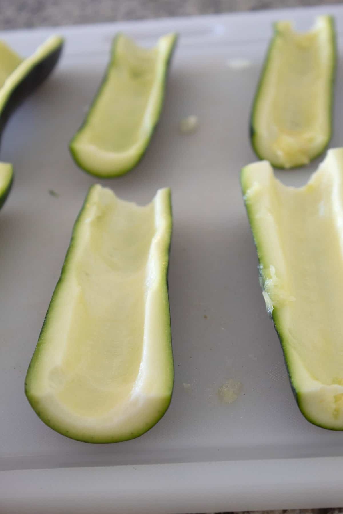 coring out zucchini boats on a cutting board