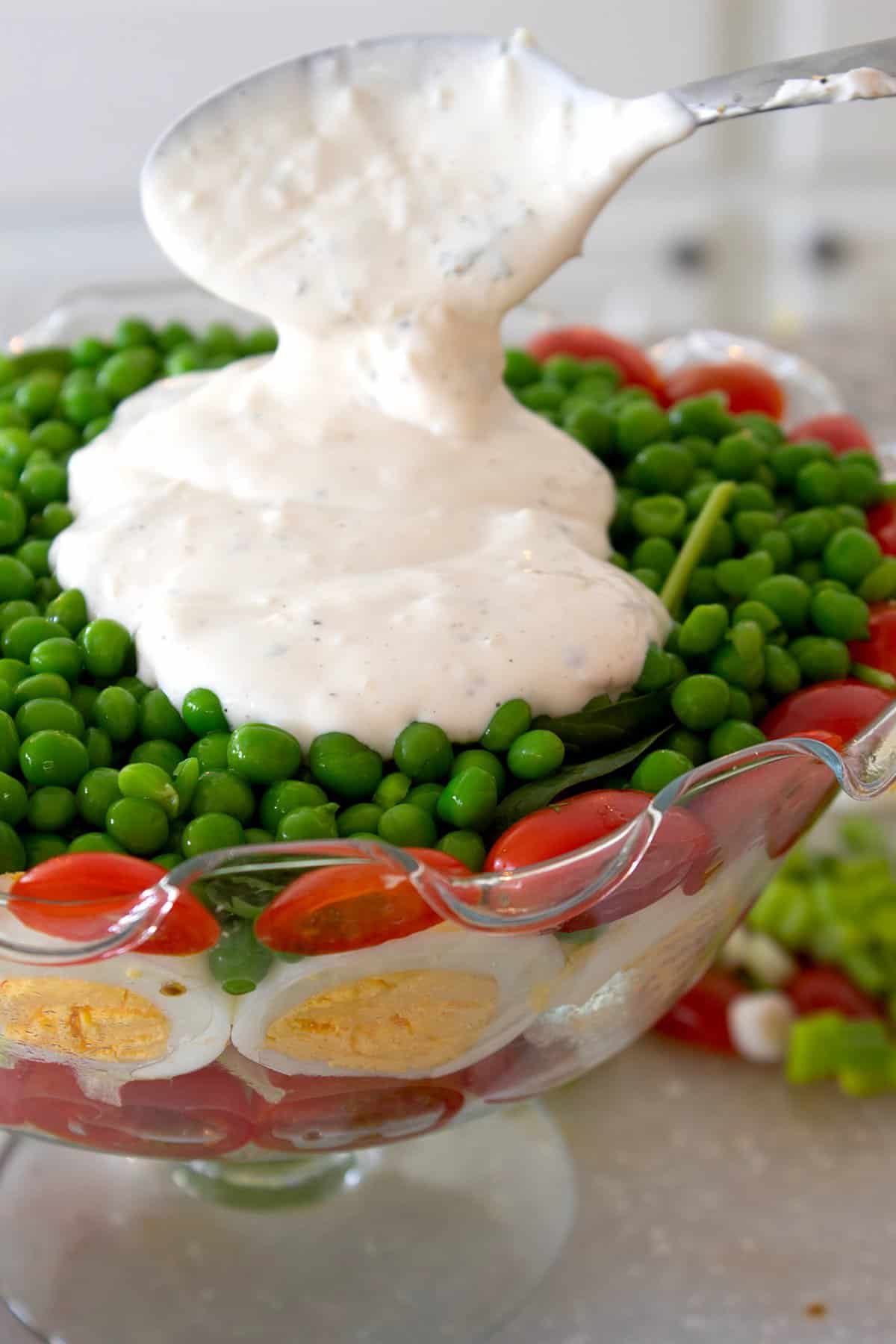 adding dressing to layered salad 