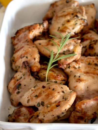 casserole pan full of cooked grilled chicken garnished with rosemary sprig