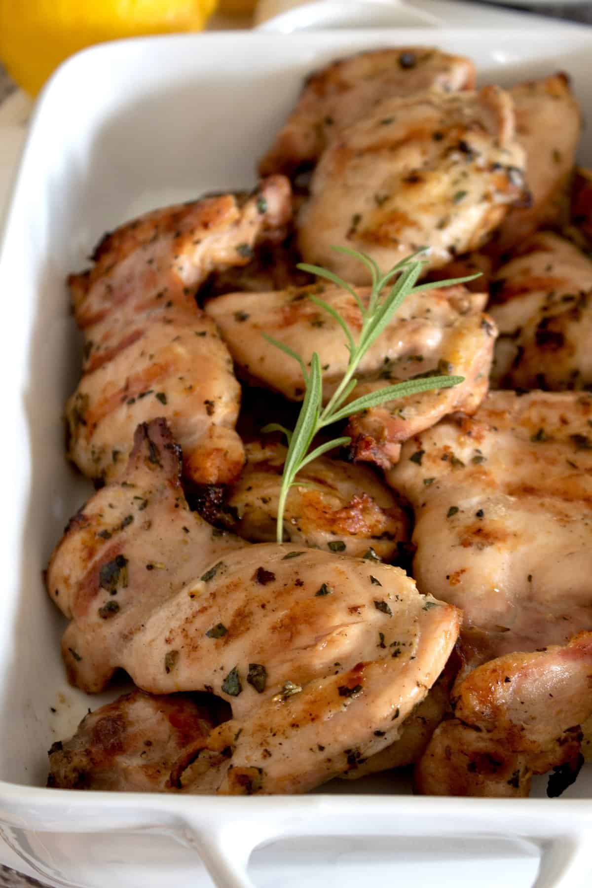 casserole pan full of cooked grilled chicken garnished with rosemary sprig