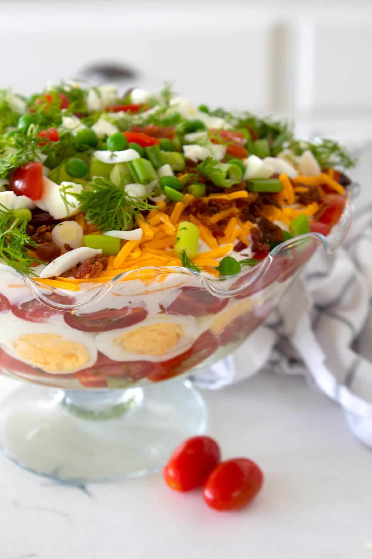 overhead view of a layered salad in a glass bowl.