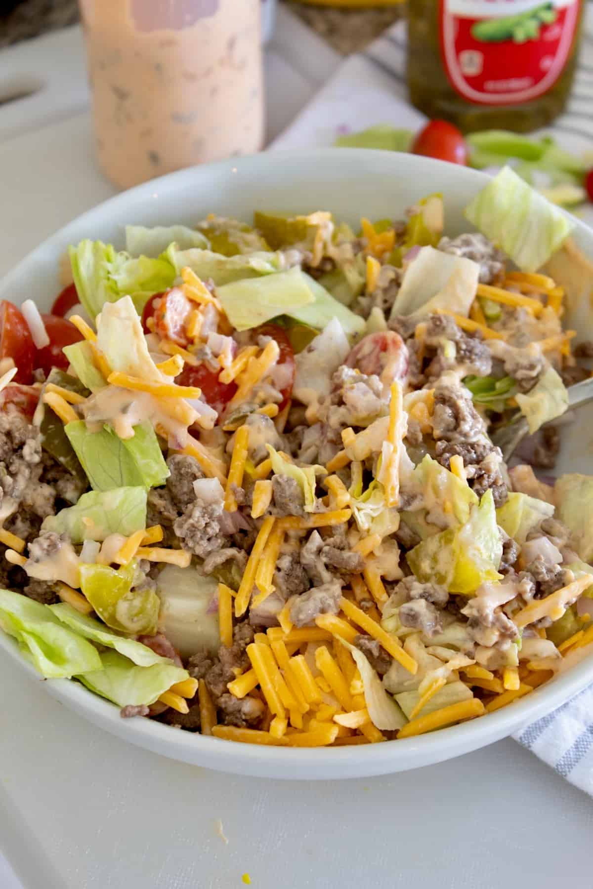 tossed cheeseburger salad in white bowl