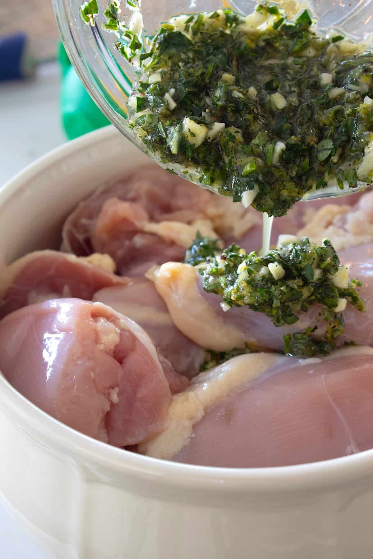 chicken thighs in a bowl with marinade pouring over the top