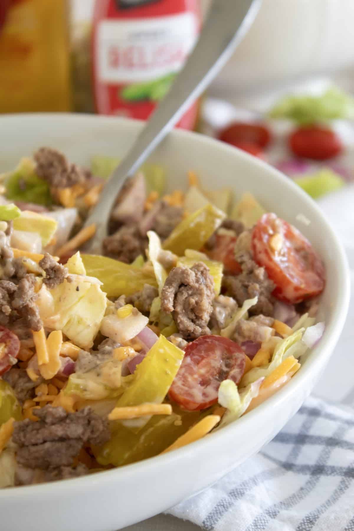 tossed burger salad in a white bowl