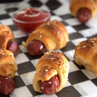 pigs in a blanket on a white and black checkered piece of food paper