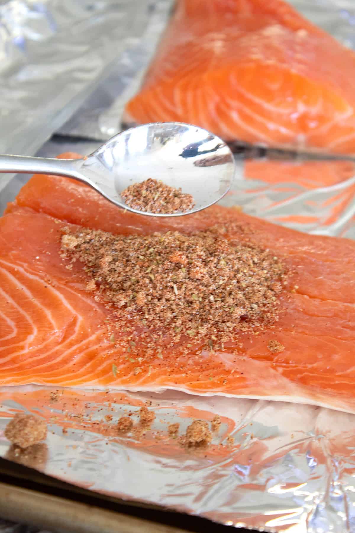 adding spices to salmon on sheet pan