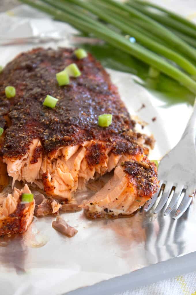 baked blackened salmon on a foil pan with a fork