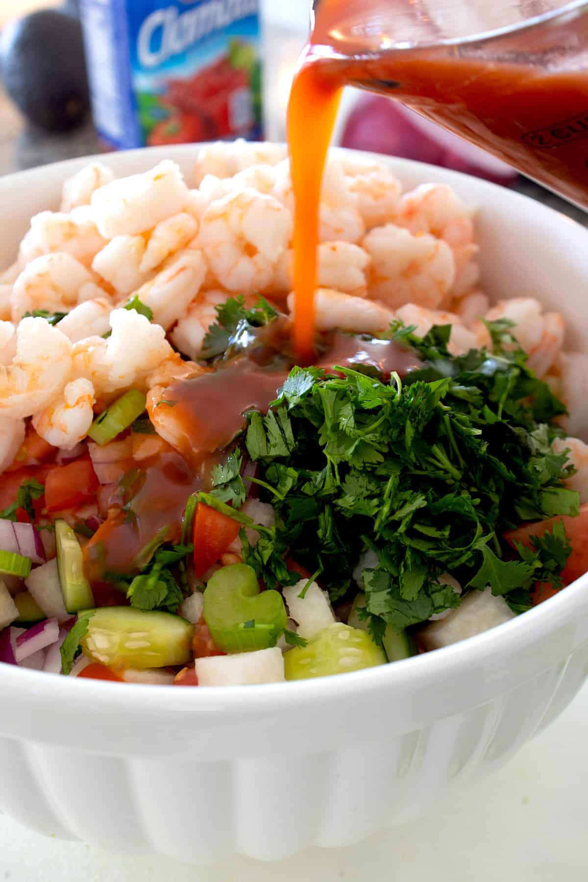 white bowl full of shrimp cocktail ingredients pouring dressing