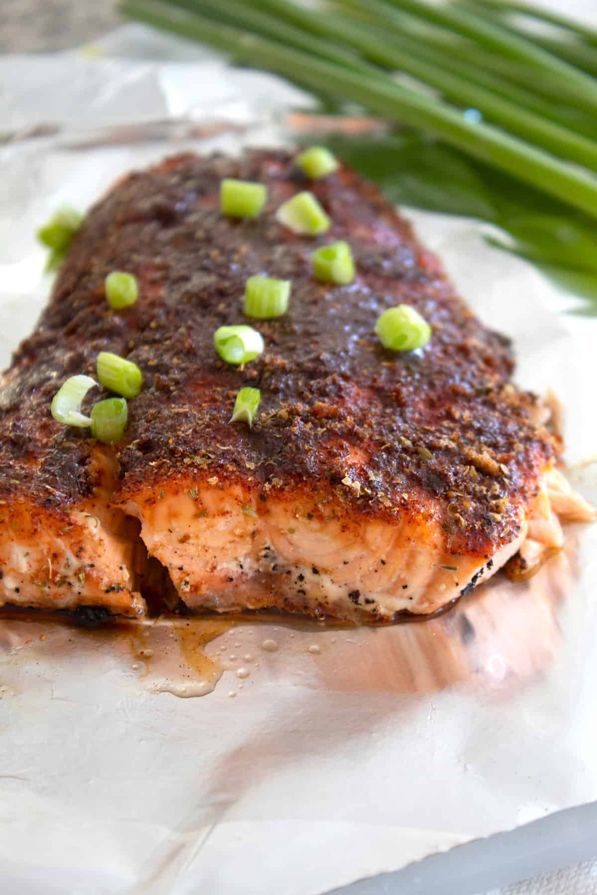 baked blackened salmon garnished with green onions on a sheet pan