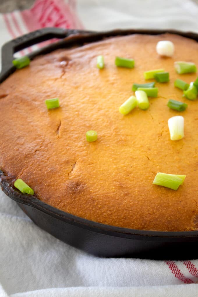 baked chili cornbread casserole in a cast iron pan with green onion garnish