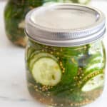 jar of refrigerator pickles on a white cutting board