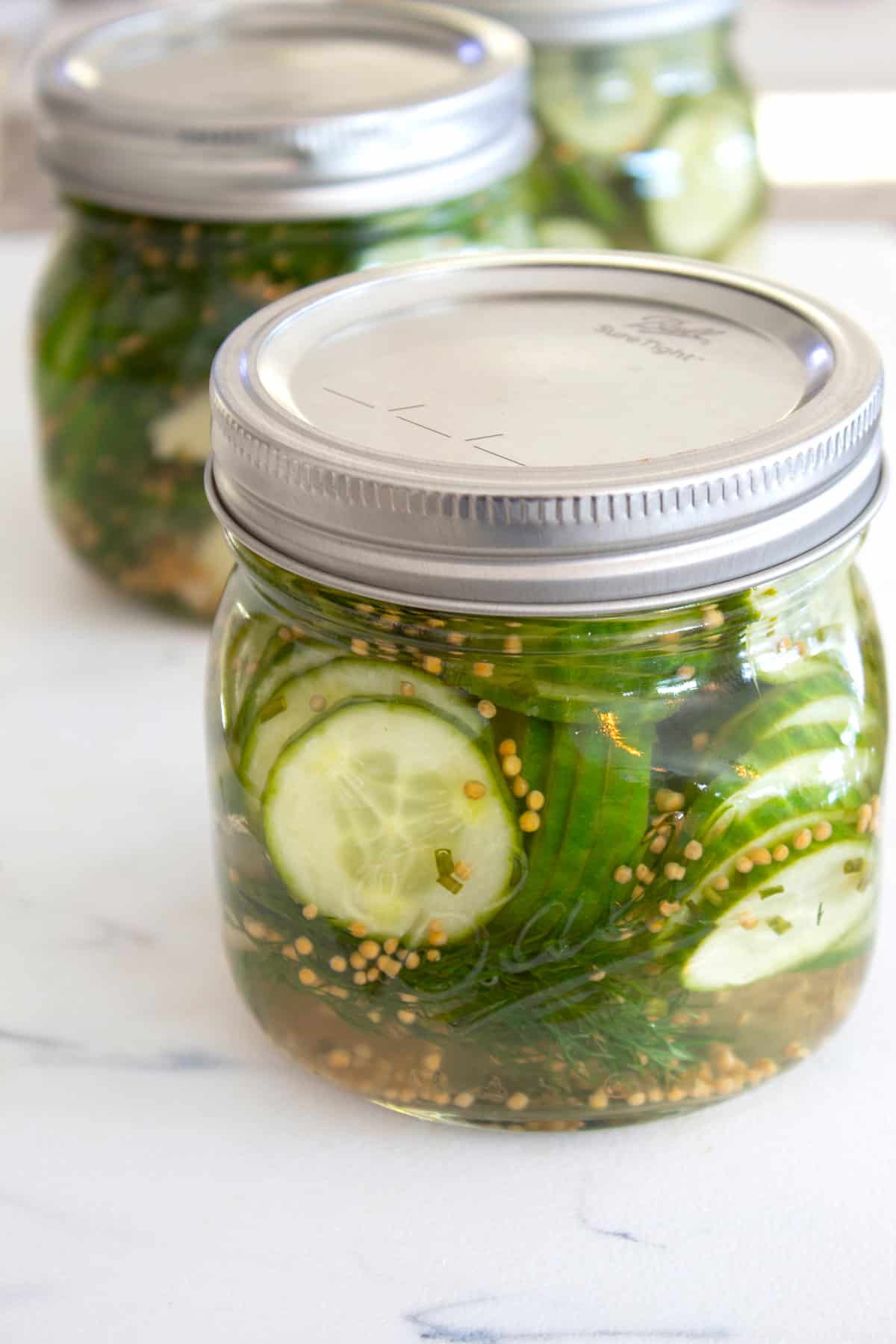 jar of refrigerator pickles on a white cutting board