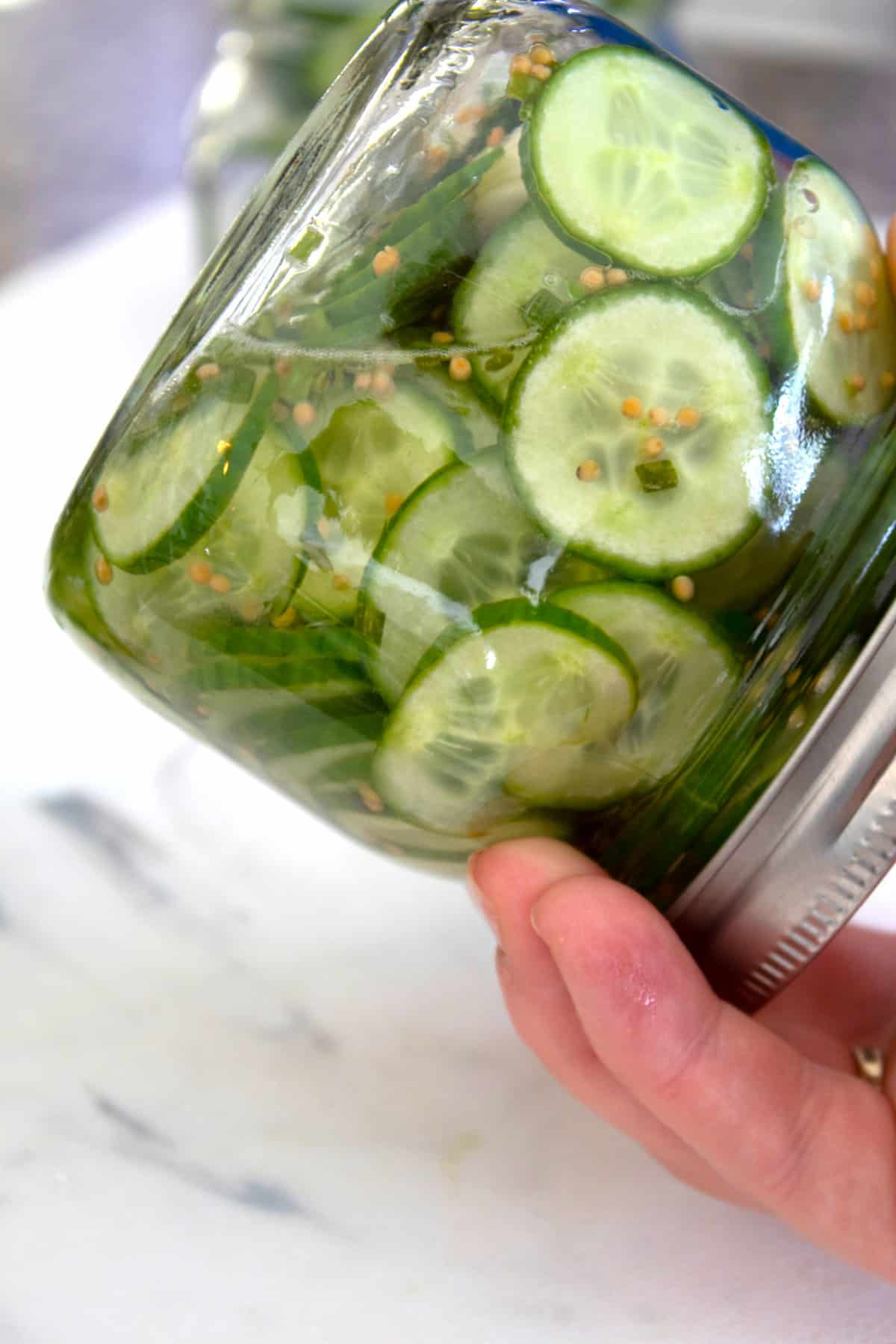 holding refrigerator pickles upside down to mix