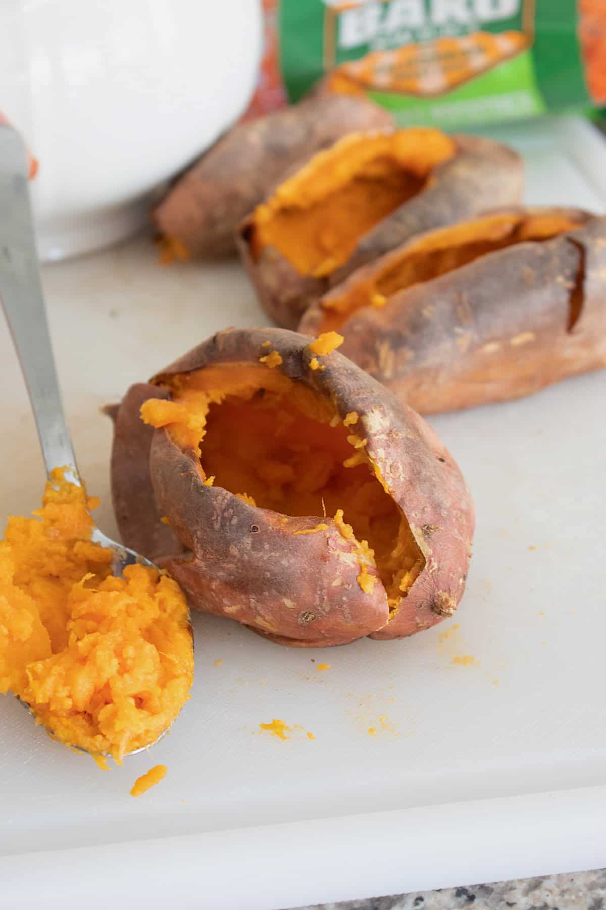 scooping sweet potato out of potato that has been cooked