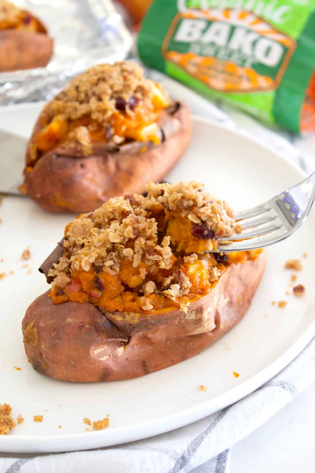 stuffed sweet potato with streusel topping on a plate with a fork 