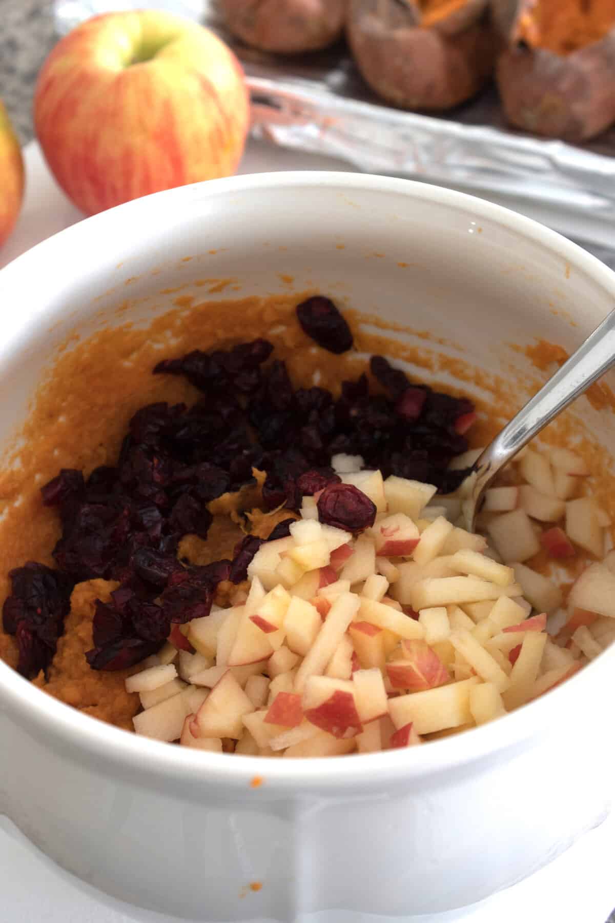 adding apples and cranberries to sweet potato mixture