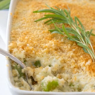 celery gratin in a white casserole dish with rosemary garnish