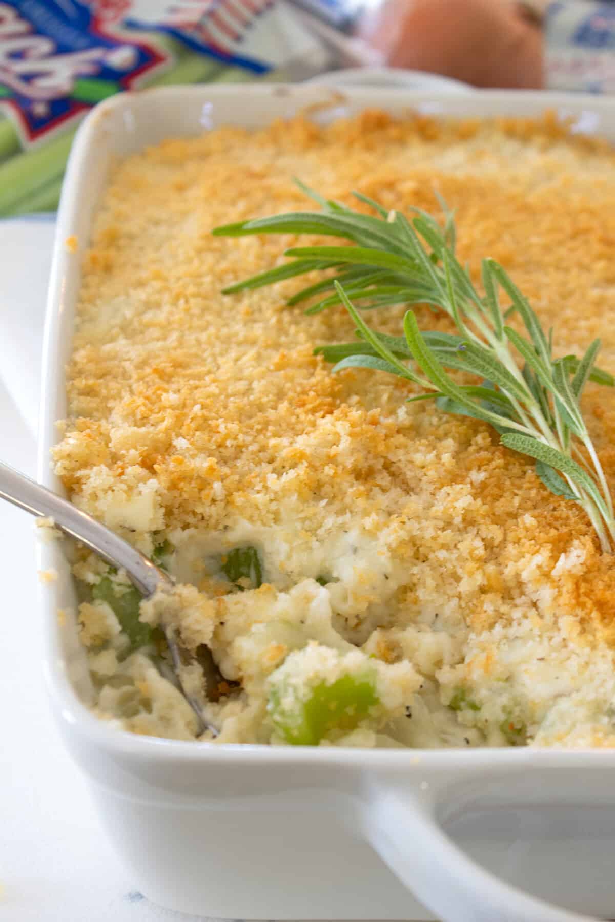 celery gratin in a white casserole dish with rosemary garnish