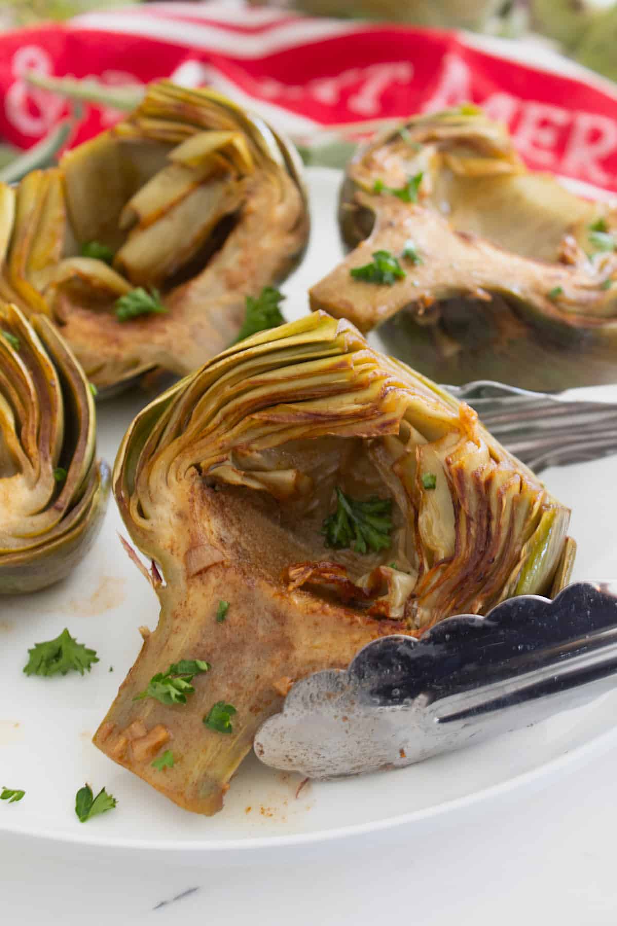 braised artichoke being held by tongs