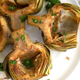 overhead view of braised artichokes on white plate