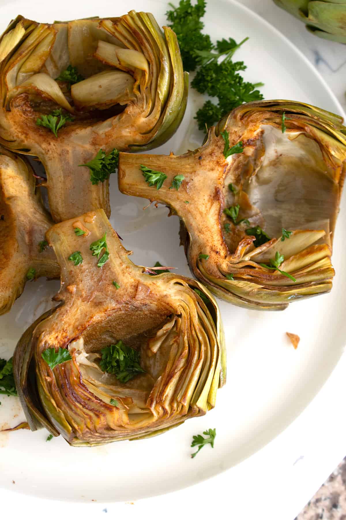 overhead view of braised artichokes on white plate