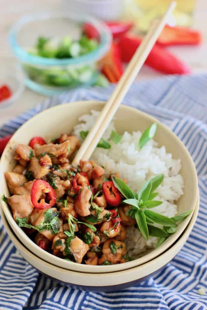Basil Chicken with white rice in bowl with chopsticks