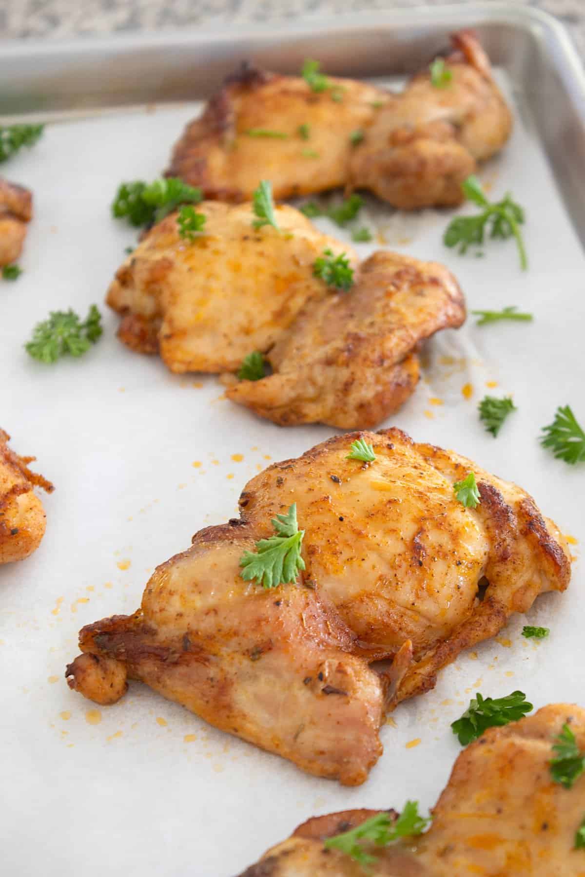 chicken thighs on sheet pan with parsley garnish