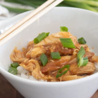 slow cooker teriyaki chicken in a white bowl with rice and chopsticks