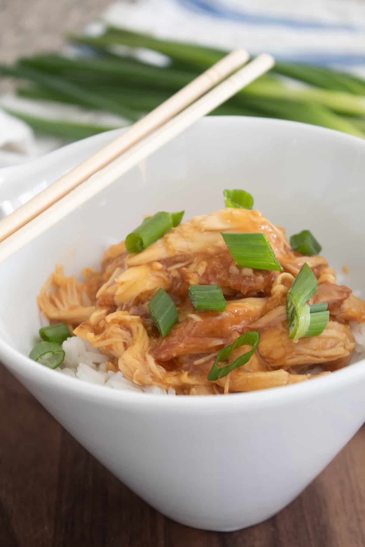 slow cooker teriyaki chicken in a white bowl with rice and chopsticks