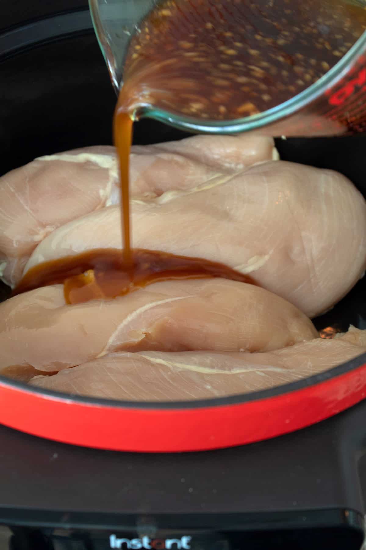 adding teriyaki sauce over chicken in slow cooker