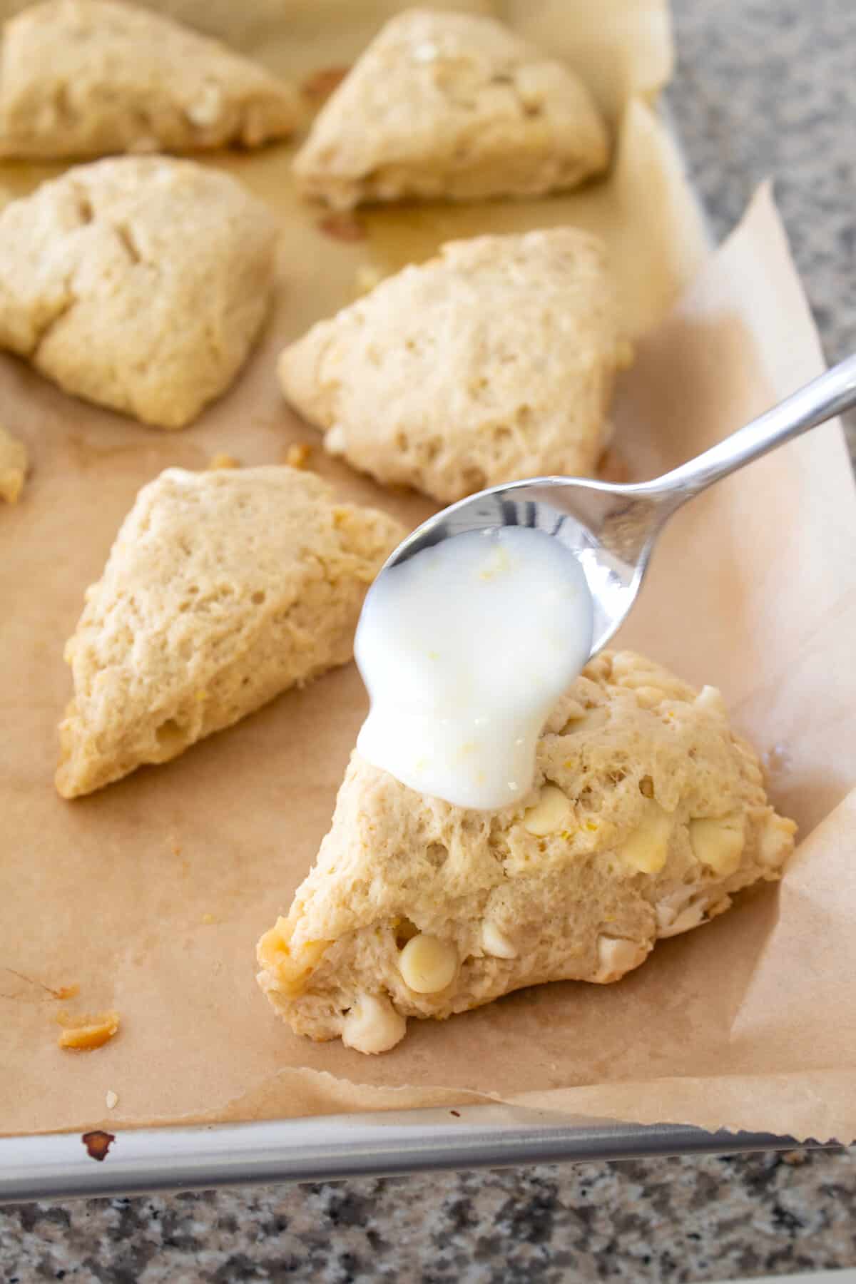 glazing a lemon scone on a sheet pan