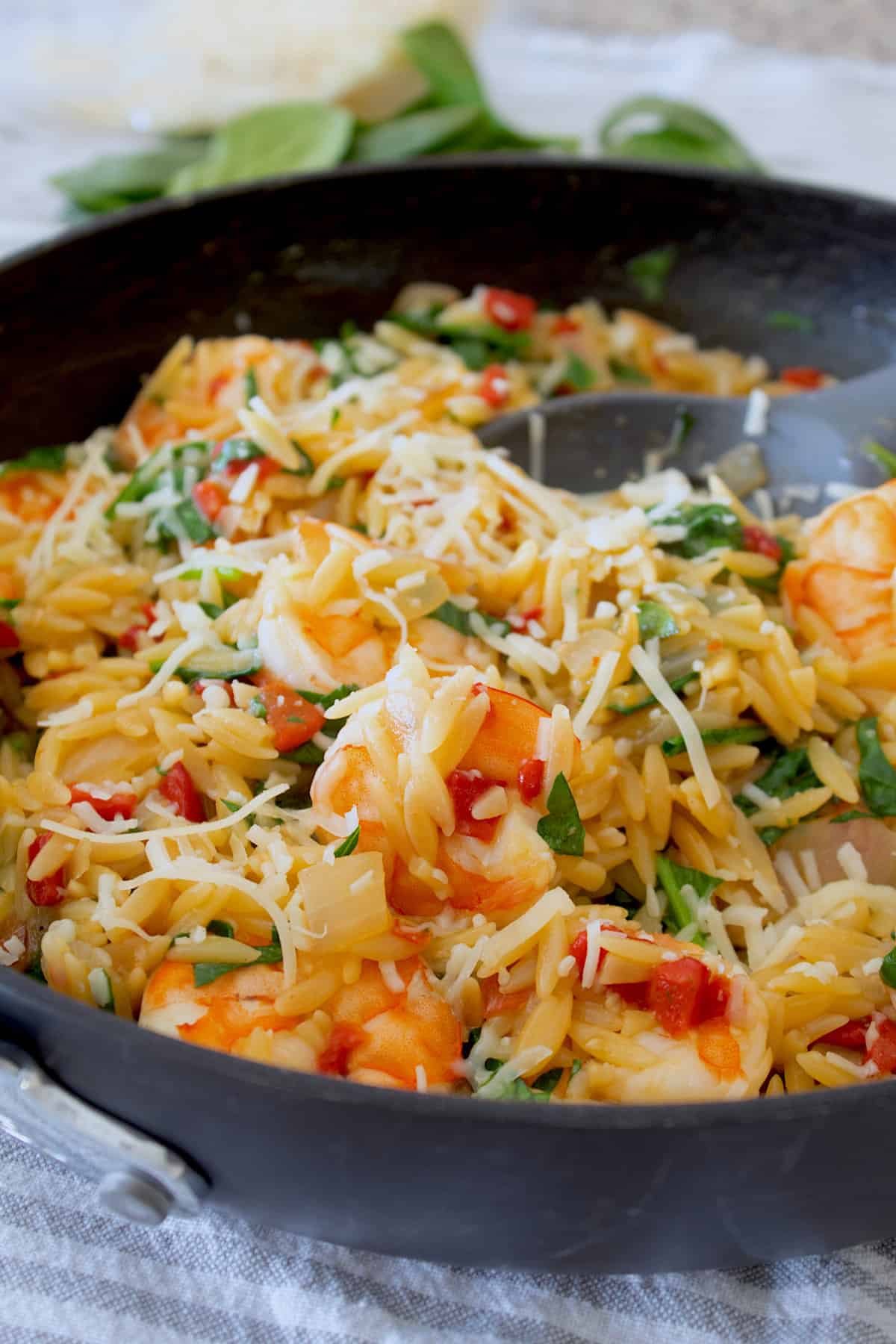 black skillet of roasted red peppers with orzo shrimp and spinach 