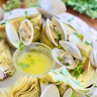 artichokes with clams on a platter with butter